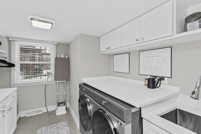 washroom with sink, cabinets, and independent washer and dryer