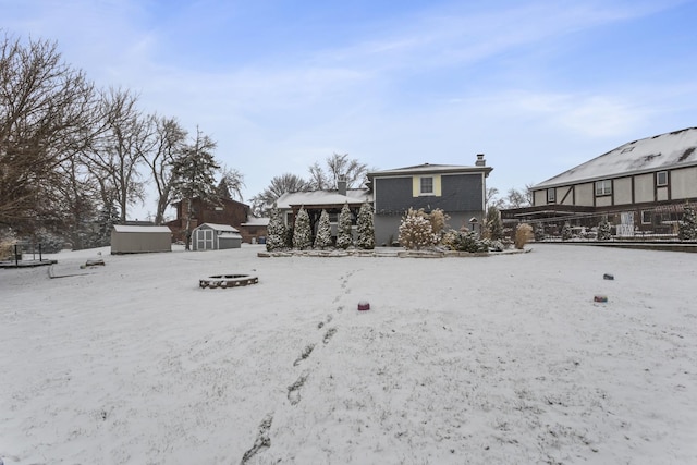 yard covered in snow featuring an outdoor fire pit and a storage shed