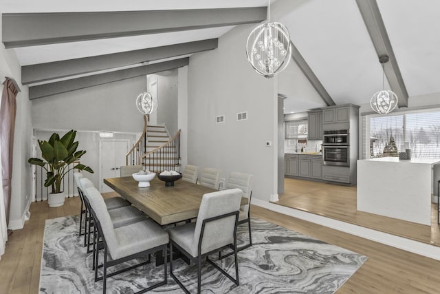 dining space with a notable chandelier, beam ceiling, high vaulted ceiling, and hardwood / wood-style flooring