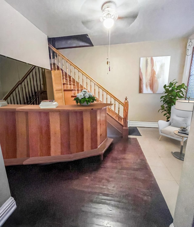 stairs featuring a baseboard radiator and ceiling fan