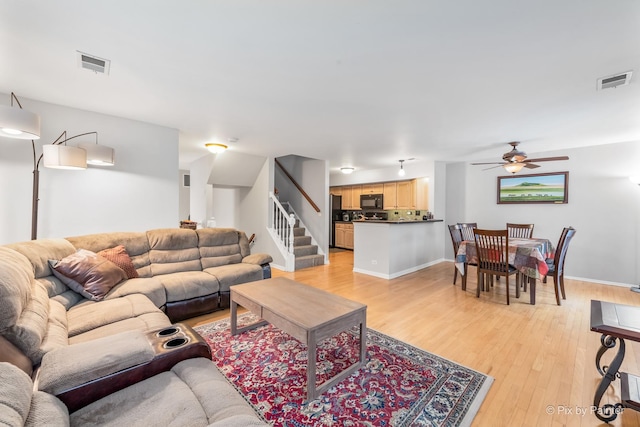 living room featuring ceiling fan and light hardwood / wood-style flooring