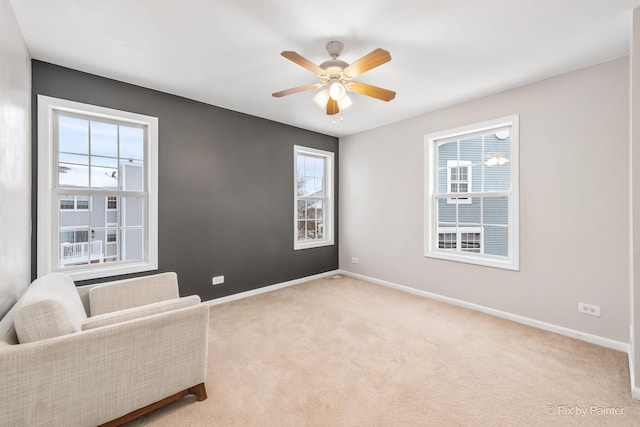 living area with light colored carpet, ceiling fan, and a wealth of natural light