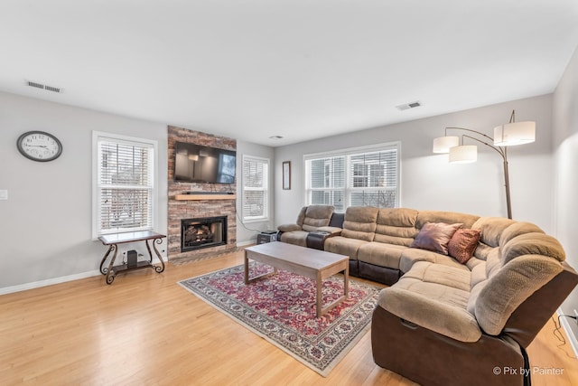 living room featuring light hardwood / wood-style floors, a healthy amount of sunlight, and a stone fireplace