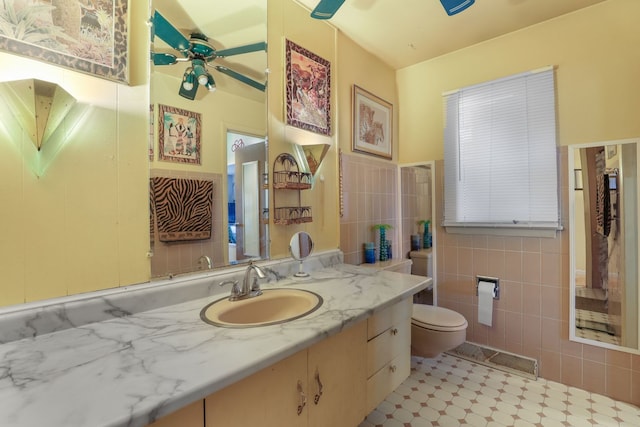 bathroom with vanity, ceiling fan, toilet, and tile walls