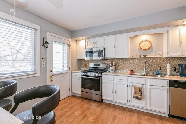 kitchen featuring light wood-type flooring, stainless steel appliances, sink, and white cabinets