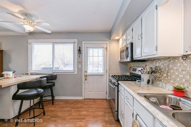 kitchen with stainless steel appliances, white cabinetry, and light wood-type flooring