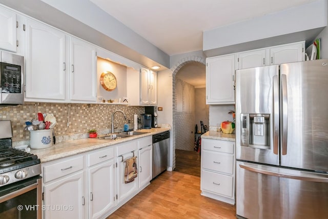 kitchen featuring tasteful backsplash, white cabinetry, appliances with stainless steel finishes, and light hardwood / wood-style flooring