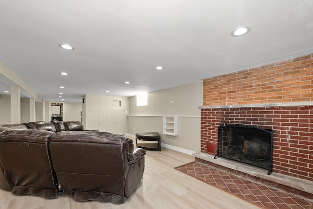 living room with a brick fireplace and light wood-type flooring