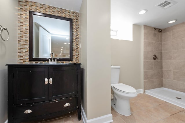 bathroom featuring tile patterned floors, vanity, toilet, and a tile shower