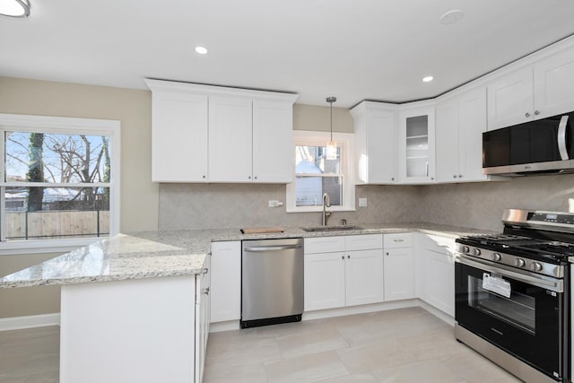 kitchen with pendant lighting, white cabinetry, sink, stainless steel appliances, and light stone countertops