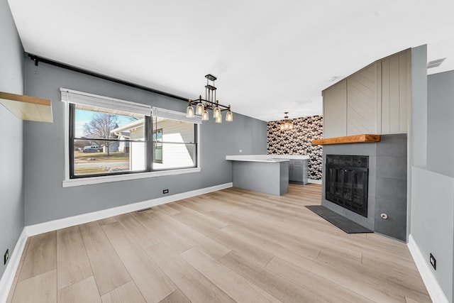 unfurnished living room with a chandelier, light wood-type flooring, and a fireplace