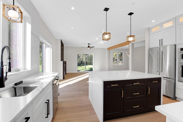 kitchen with ceiling fan, sink, stainless steel appliances, decorative light fixtures, and white cabinets