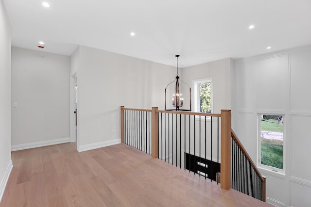 corridor featuring an inviting chandelier and light hardwood / wood-style flooring