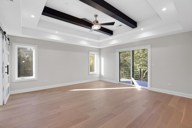 interior space featuring a barn door, a tray ceiling, ceiling fan, and light hardwood / wood-style floors