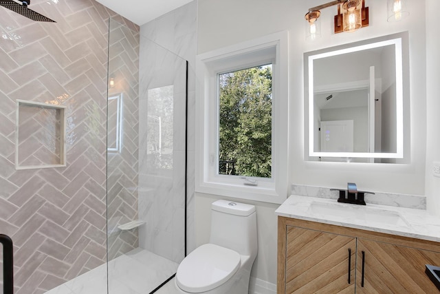 bathroom featuring a tile shower, vanity, and toilet