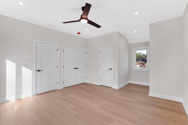 unfurnished bedroom with ceiling fan, two closets, lofted ceiling, and light hardwood / wood-style flooring