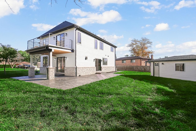 back of property featuring a yard, a balcony, and a patio area