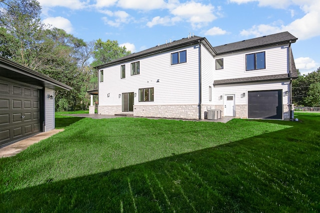 rear view of property featuring a garage, a lawn, and central air condition unit