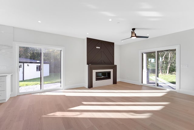 unfurnished living room with ceiling fan, light hardwood / wood-style floors, and a fireplace