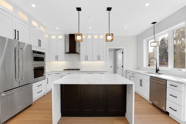 kitchen with a center island, sink, stainless steel appliances, wall chimney range hood, and white cabinets