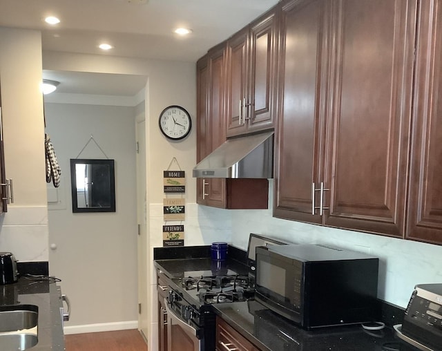 kitchen featuring black gas stove, dark wood-type flooring, exhaust hood, and dark stone counters