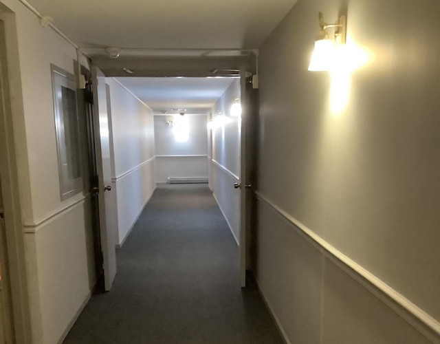 hall with a baseboard radiator and dark colored carpet