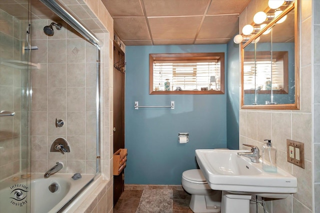 full bathroom with sink, plenty of natural light, bath / shower combo with glass door, and toilet