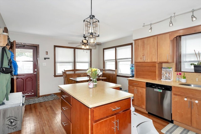 kitchen featuring hanging light fixtures, light hardwood / wood-style flooring, stainless steel dishwasher, ceiling fan, and a kitchen island