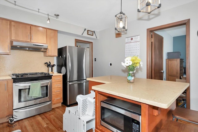 kitchen with a center island, hanging light fixtures, stainless steel appliances, a kitchen breakfast bar, and backsplash