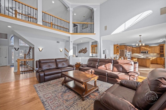 living room with a high ceiling, light hardwood / wood-style flooring, and a chandelier