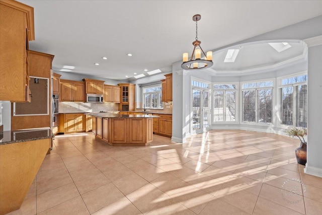 kitchen with stainless steel appliances, backsplash, a kitchen island, a chandelier, and pendant lighting