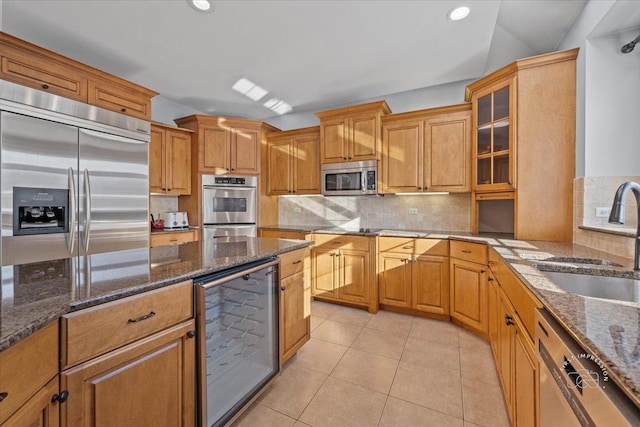 kitchen with decorative backsplash, beverage cooler, appliances with stainless steel finishes, dark stone countertops, and sink