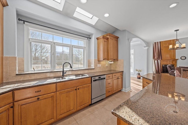 kitchen with stainless steel dishwasher, a notable chandelier, decorative backsplash, light tile patterned flooring, and sink