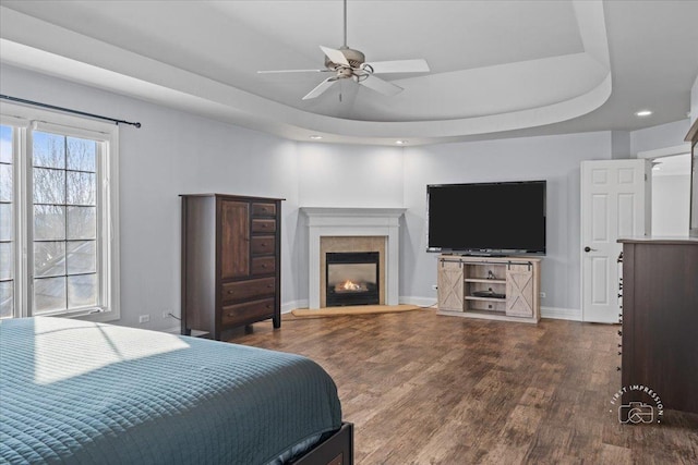 bedroom featuring ceiling fan, hardwood / wood-style floors, and a raised ceiling