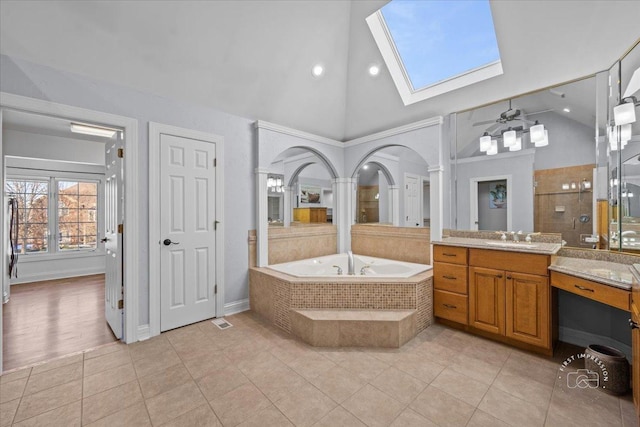 bathroom with tile patterned flooring, vaulted ceiling with skylight, ceiling fan, separate shower and tub, and vanity