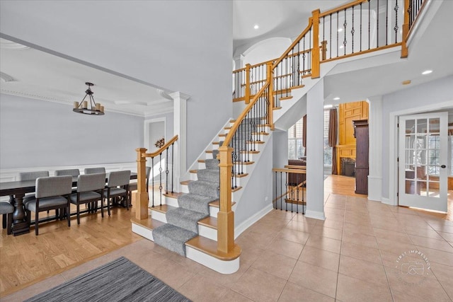 stairway with tile patterned floors, decorative columns, and ornamental molding