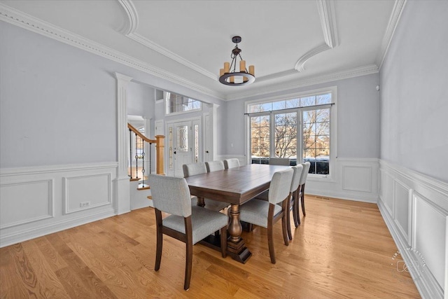 dining area with a notable chandelier, crown molding, and light hardwood / wood-style flooring