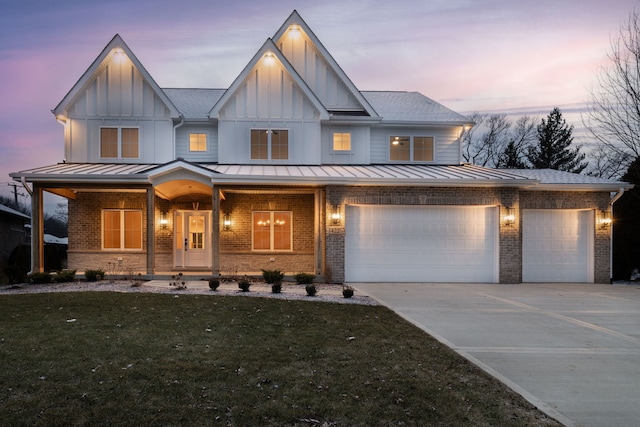 view of front of house with a porch, a yard, and a garage