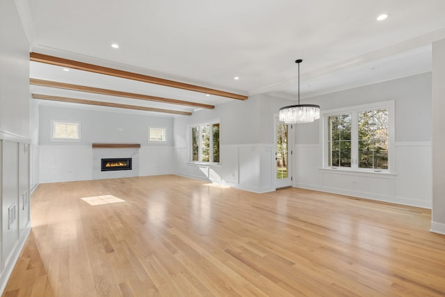 unfurnished living room with a fireplace, light hardwood / wood-style flooring, beamed ceiling, and a notable chandelier