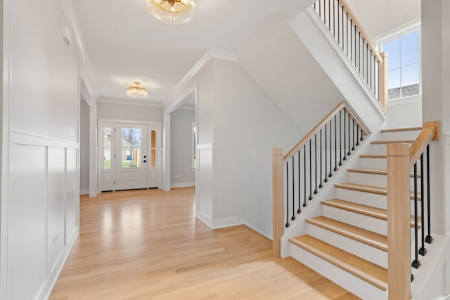 entrance foyer featuring plenty of natural light, light hardwood / wood-style flooring, a notable chandelier, and ornamental molding