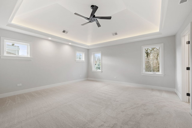 carpeted spare room with ceiling fan and a tray ceiling