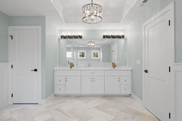 bathroom featuring a raised ceiling, vanity, and a notable chandelier