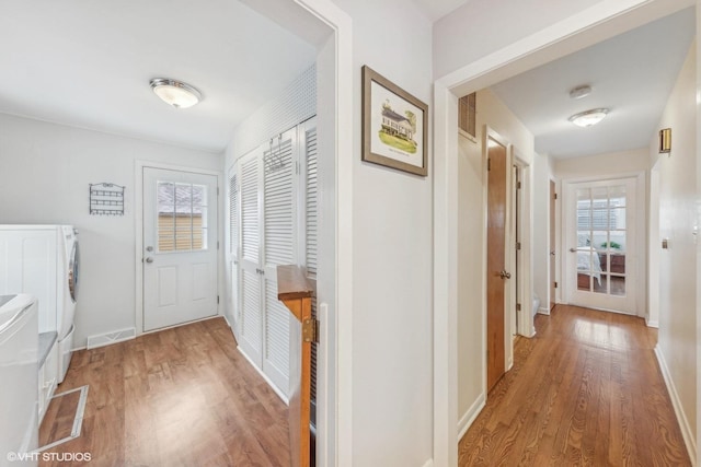 hallway with washing machine and dryer, plenty of natural light, and wood-type flooring