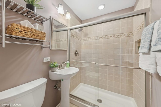 bathroom featuring a shower with door and toilet