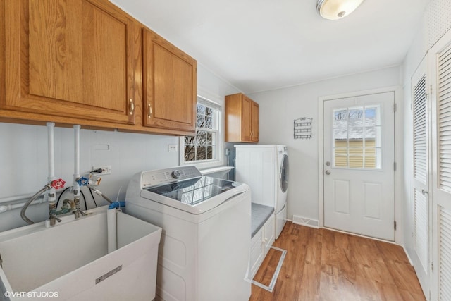 laundry area featuring cabinets, sink, independent washer and dryer, and light hardwood / wood-style floors