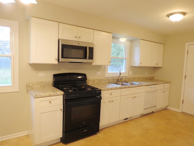 kitchen with black range with gas stovetop, white cabinetry, sink, and white dishwasher