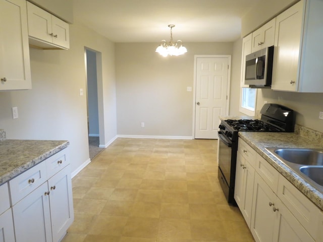 kitchen featuring a chandelier, black range with gas stovetop, white cabinetry, and hanging light fixtures