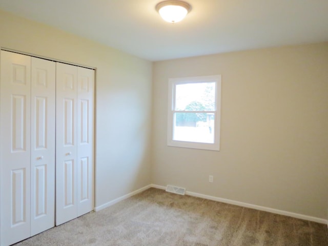 unfurnished bedroom featuring a closet and light colored carpet