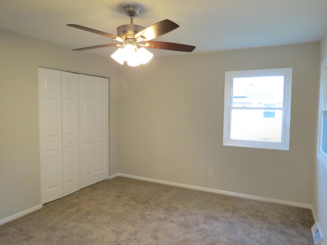 unfurnished bedroom with ceiling fan, light carpet, and a closet