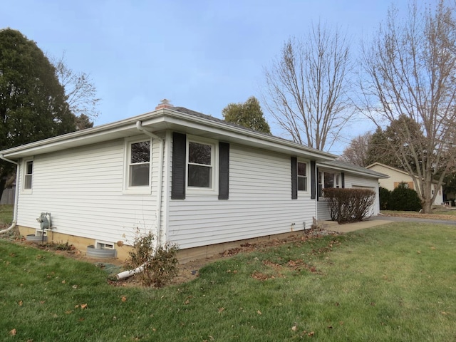 view of side of home featuring a lawn and a garage